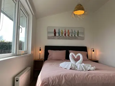 a bedroom with a bed with two swans in the shape of hearts at NEW - The Surf Shack - on a lake near Amsterdam! in Vinkeveen
