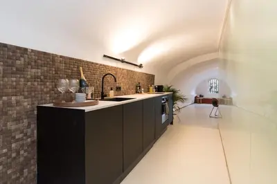 a kitchen with black cabinets and a brick wall at Wellness Apartment on the Wharf Utrecht in Utrecht