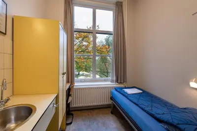 a bathroom with a bed and a sink and a window at Stayokay Hostel Utrecht - Bunnik in Bunnik