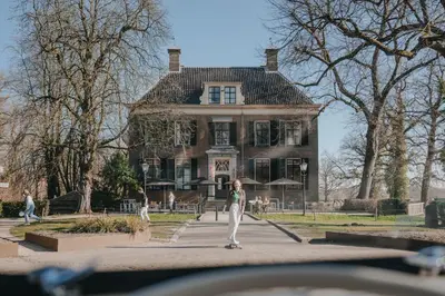 a woman riding a skateboard in front of a house at Stayokay Hostel Utrecht - Bunnik in Bunnik