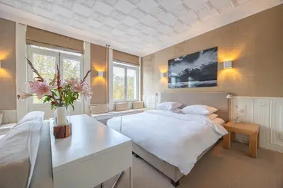 a bedroom with a white bed and a vase of flowers at Park Mansion Hotel in Amsterdam
