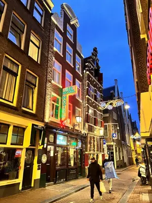 a person walking down a city street at night at The Old Nickel Hotel in Amsterdam
