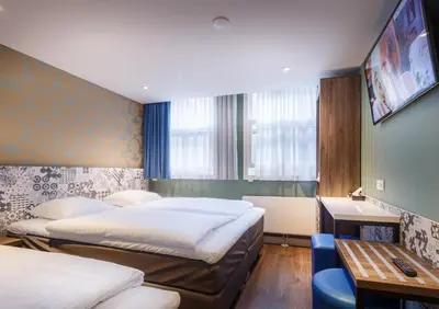 a hotel room with two beds and a desk and a table at The Old Nickel Hotel in Amsterdam