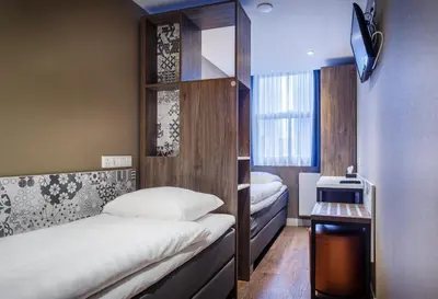 a small room with two beds and a window at The Old Nickel Hotel in Amsterdam