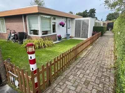 a house with a fence with a lighthouse on it at Vakantiebungalow in Riviera Maison stijl nabij zee en strand, bos en duin in Warmenhuizen