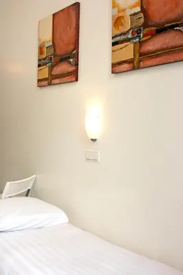a bedroom with a bed and two paintings on the wall at MAX Hotel Amsterdam in Amsterdam