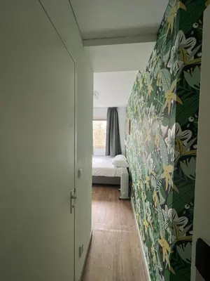 a bedroom with a bed and a wall with floral wallpaper at MAX Hotel Amsterdam in Amsterdam