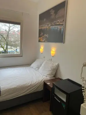 a small bedroom with a bed and a window at MAX Hotel Amsterdam in Amsterdam