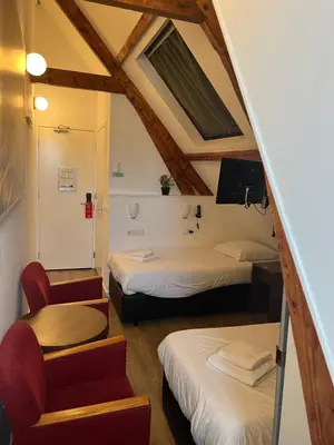 a small room with two beds and a chair at MAX Hotel Amsterdam in Amsterdam