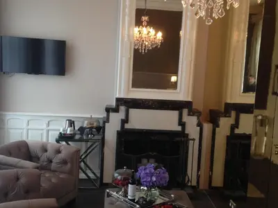 a living room with a fireplace and a chandelier at Apple Inn Hotel in Amsterdam