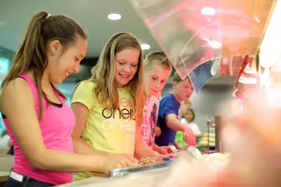 a group of people standing around a counter preparing food at Stayokay Hostel Egmond in Egmond-Binnen