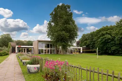 a building with a fence and a field with flowers at Stayokay Hostel Egmond in Egmond-Binnen