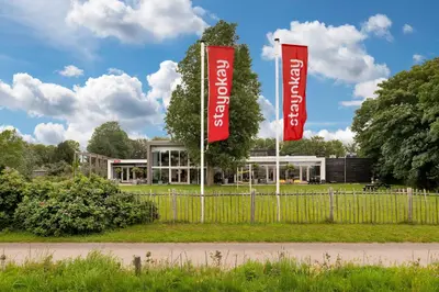 two red banners on poles in front of a building at Stayokay Hostel Egmond in Egmond-Binnen