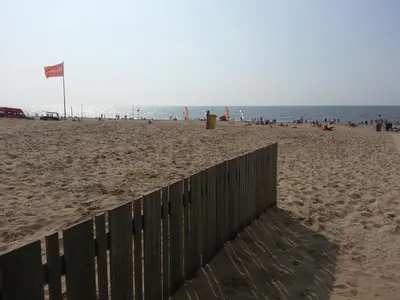 a fence on a beach with a group of people at Appartement 