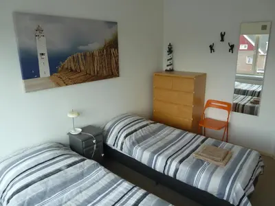 two beds in a bedroom with a picture of a lighthouse at Appartement 