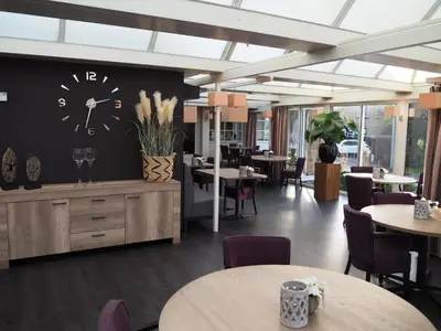a restaurant with tables and a clock on the wall at Hotel De Zoete Inval Haarlemmerliede in Haarlem