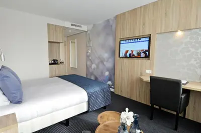 a hotel room with a bed and a desk and a tv at Hotel De Zoete Inval Haarlemmerliede in Haarlem