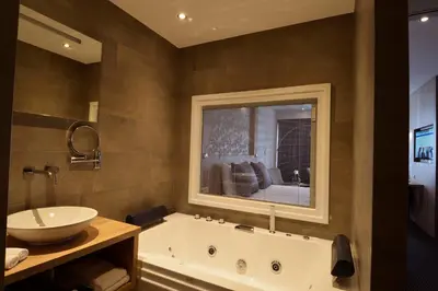 a bathroom with a tub and a sink and a mirror at Hotel De Zoete Inval Haarlemmerliede in Haarlem