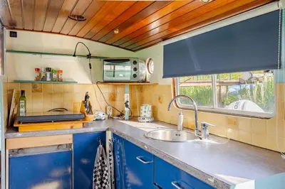 a kitchen with blue cabinets and a sink and a window at Floating B&B Amsterdam in Amsterdam