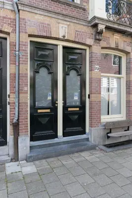 a pair of black doors on a brick building at Vondel 99 in Amsterdam
