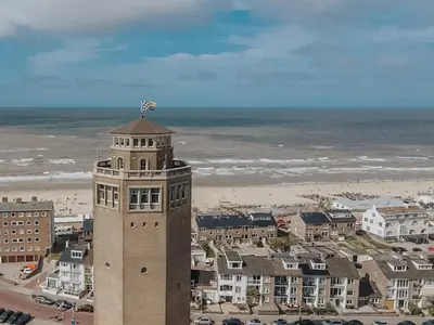 a building with a flag on top of it next to a beach at Appartement en Studio Papillon in Zandvoort