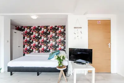 a bedroom with a bed with a floral wallpaper at Appartement en Studio Papillon in Zandvoort