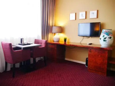 a hotel room with a desk with a television and chairs at Hotel het Oosten in Alphen aan den Rijn