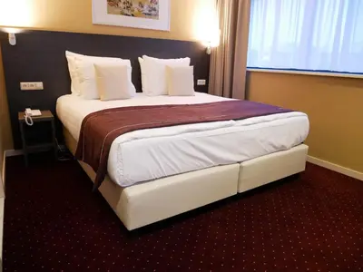 a hotel room with a large bed in a room at Hotel het Oosten in Alphen aan den Rijn