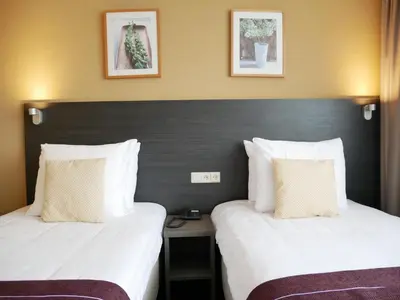 two beds in a hotel room with white sheets at Hotel het Oosten in Alphen aan den Rijn