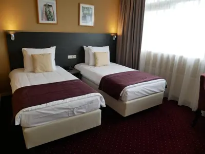 a hotel room with two beds and a window at Hotel het Oosten in Alphen aan den Rijn