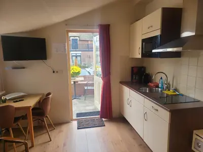 a kitchen with a table and a dining room at Appartement Canberra. in Bergen aan Zee