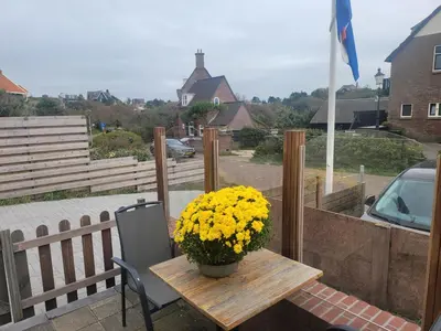 a wooden table with yellow flowers on a patio at Appartement Canberra. in Bergen aan Zee