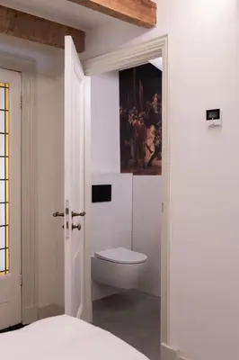 a bathroom with a toilet and a painting on the wall at This Must Be The Place in Utrecht