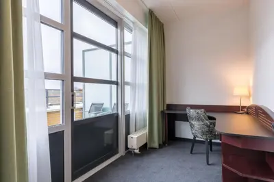 a room with a desk and a large window at Amrâth Hotel Alkmaar in Alkmaar