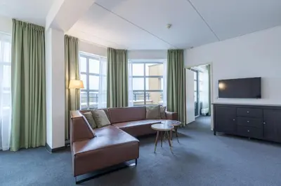 a living room with a couch and a tv at Amrâth Hotel Alkmaar in Alkmaar