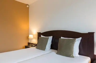a bedroom with two beds and a night stand with a lamp at Amrâth Hotel Alkmaar in Alkmaar