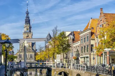 a bridge over a river in a city with a clock tower at Amrâth Hotel Alkmaar in Alkmaar