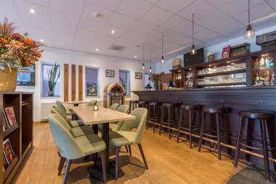 a restaurant with a table and chairs and a bar at Amrâth Hotel Alkmaar in Alkmaar