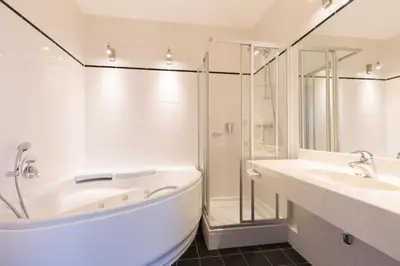 a white bathroom with a tub and a shower at Amrâth Hotel Alkmaar in Alkmaar