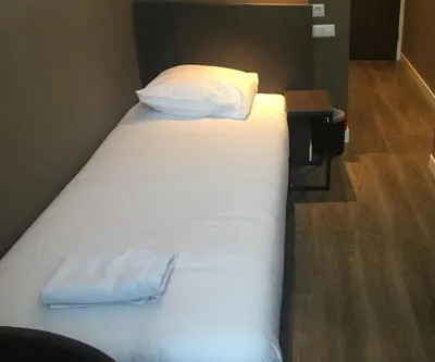 a large white bed with two pillows and a table at Hotel Manofa in Amsterdam
