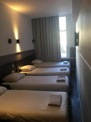 a row of four beds in a hotel room at Hotel Manofa in Amsterdam