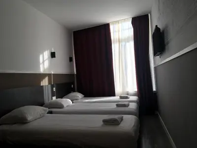 three beds in a hotel room with a window at Hotel Manofa in Amsterdam