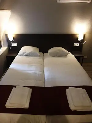 a bedroom with two beds with white sheets and pillows at Hotel Manofa in Amsterdam