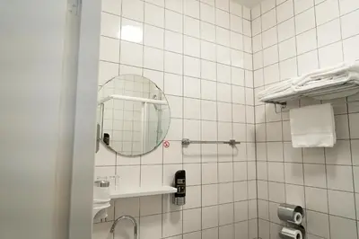 a white tiled bathroom with a mirror and a sink at Het Hart van Weesp in Weesp