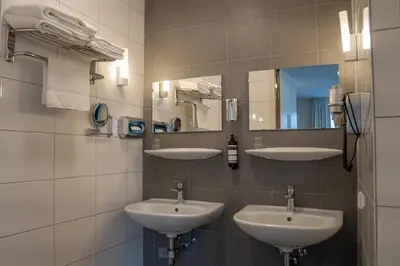 a bathroom with three sinks and a mirror at Het Hart van Weesp in Weesp