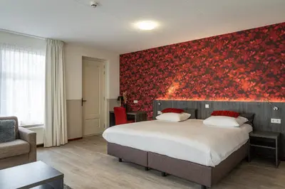 a bedroom with a bed and a red wall at Het Hart van Weesp in Weesp