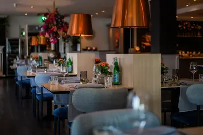 a row of tables in a restaurant with blue chairs at Tulip Inn Leiden Centre in Leiden