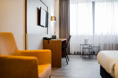 a hotel room with a bed and a chair and a table at Tulip Inn Leiden Centre in Leiden