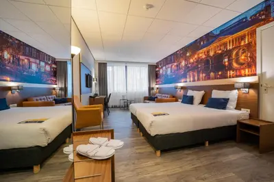 a hotel room with two beds and a desk at Tulip Inn Leiden Centre in Leiden
