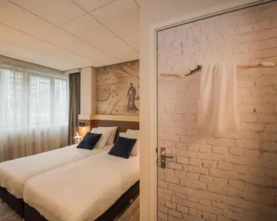 a bedroom with a bed and a brick wall at Tulip Inn Leiden Centre in Leiden